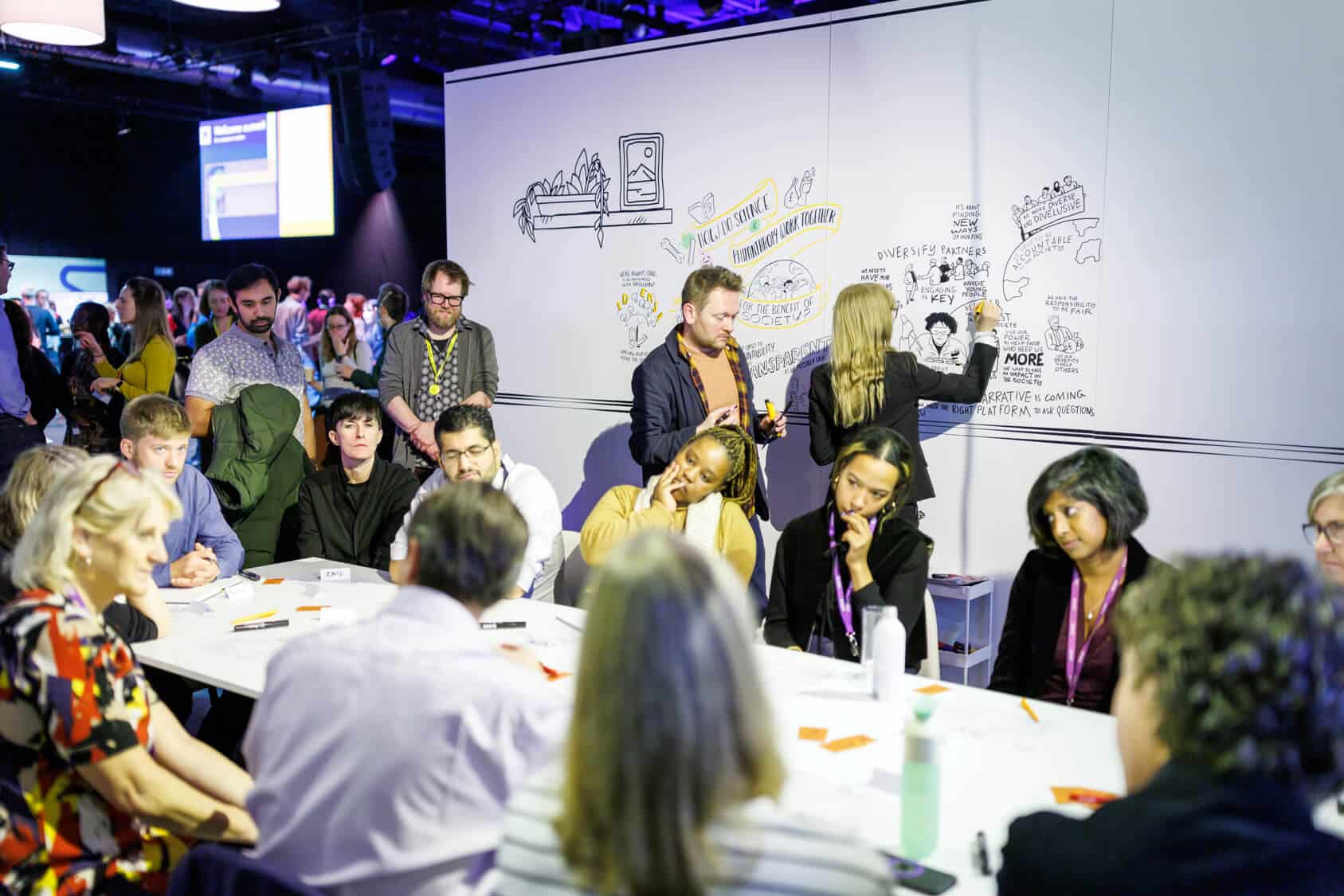 Smartup Visuals’ live scribers in action at the Wellcome Trust event, illustrating key discussions in real time while attendees engage in thoughtful conversation at a roundtable.