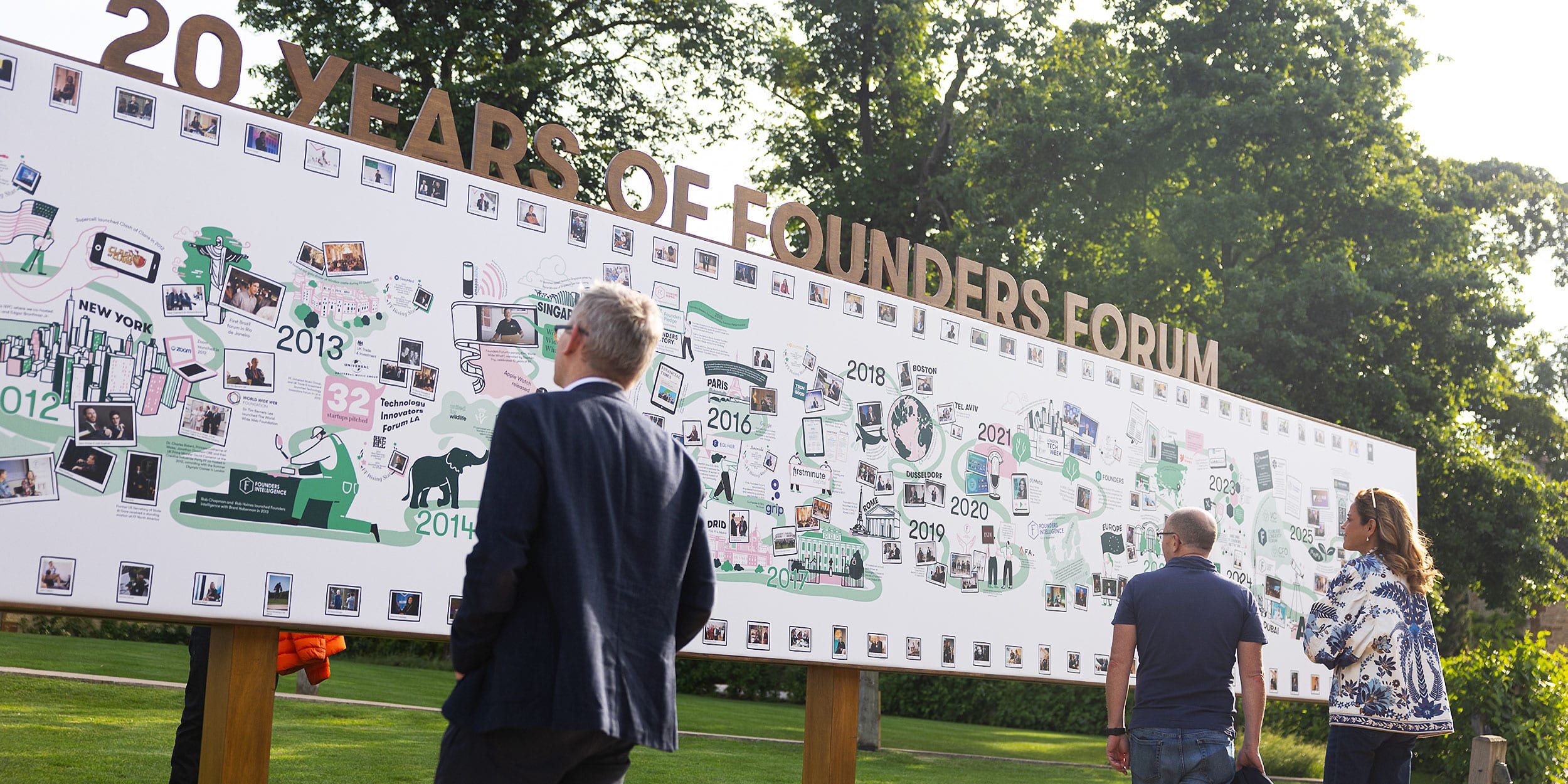 Audience engaging with a large-scale illustrated event wall mural at Founders Forum’s 20-year celebration
